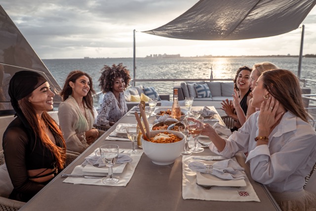 Couple posing on yacht bow at golden hour with Miami skyline behind